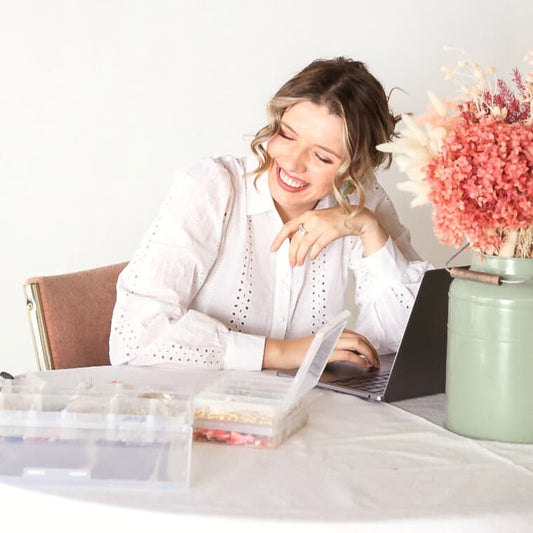 Mazana in her home office smiling looking blissful surrounded by paints. 