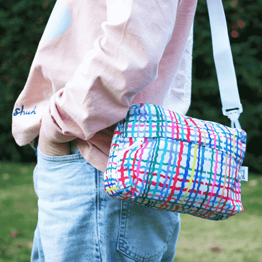 Shuh Lee's Wave Everyday Shoulder Bag: a small, rectangular bag with a white background and a cross hatch of colourful, wiggly stripes in every colour. 