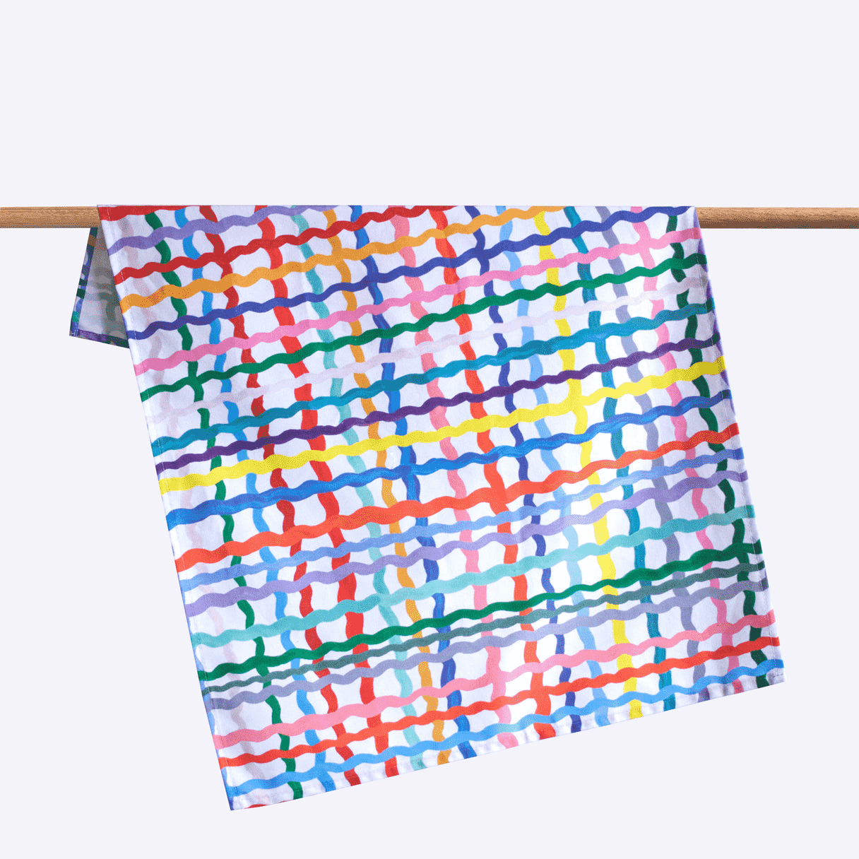 Shuh Lee Wave Tea Towel: A white background with squiggly, colourful lines running across in a patchwork design. 