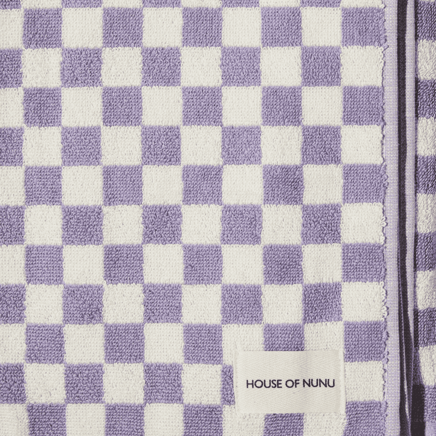 A close up of a white & lilac check hand towel by House of Nunu. 