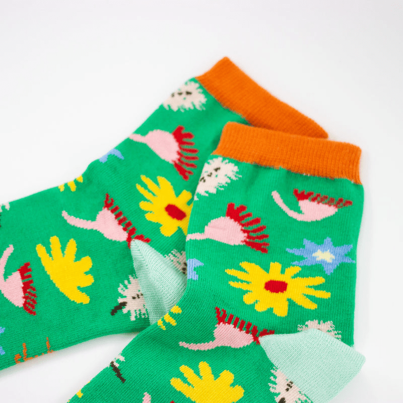 Meadow Socks: A gorgeous homage to nature, these socks have a bright green backdrop with scattered Australian florals across the print with orange accents on the top and toes of the socks. 