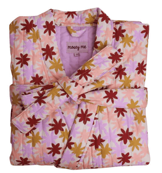 A folded quilted robe by Mosey Me, neatly arranged into a perfect square. The robe features a cream-colored background adorned with small daisy-like flowers in burgundy, mustard yellow, and baby pink. A matching tie, designed to wrap around the middle, is tucked neatly alongside the robe, highlighting its cozy yet elegant design.