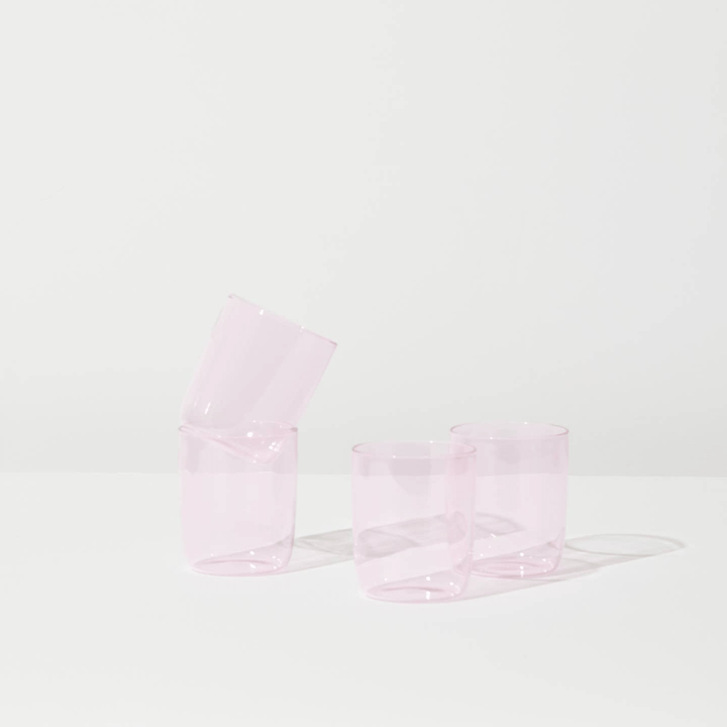 Pink drinking glasses by house of Nunu: A beautiful soft, pastel pink colour. Four of them next to each other, two resting on a brown box that reads "House of Nunu". 