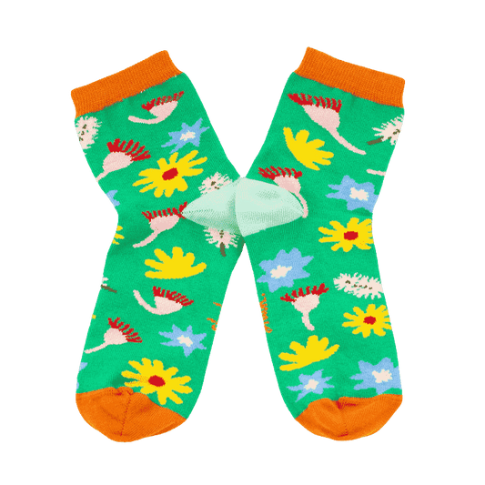 Meadow Socks: A gorgeous homage to nature, these socks have a bright green backdrop with scattered Australian florals across the print with orange accents on the top and toes of the socks. 