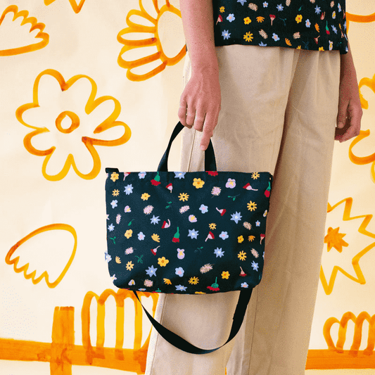 Shuh Lee's vibrant handbag with shoulder strap: A joyful design with a forest green background and tiny pieces of nature scattered across including bottle brushes, daisies, leaves and other Australian fauna. 