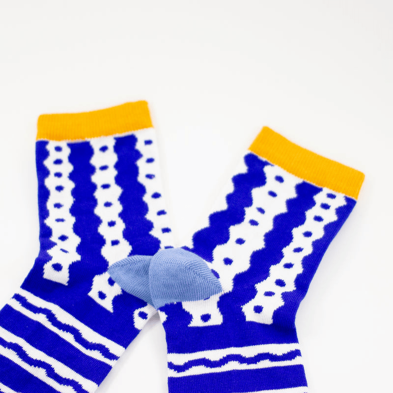 Shuh Lee Socks: Blue and white with a squiggle line design across the pattern with yellow splashes of colour at the toes and tops of each sock. 