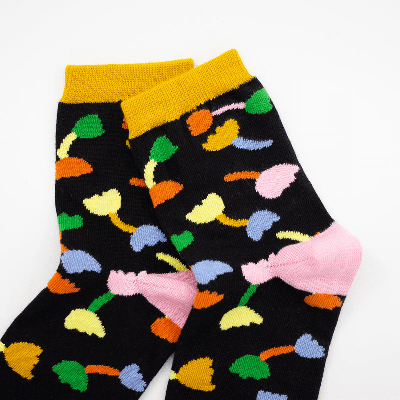 Shuh Lee Tulip Socks: A super cute design with a black backdrop and multicoloured tulips scattered across with green, pink and yellow splashes of colour at the top, heel and toe. 