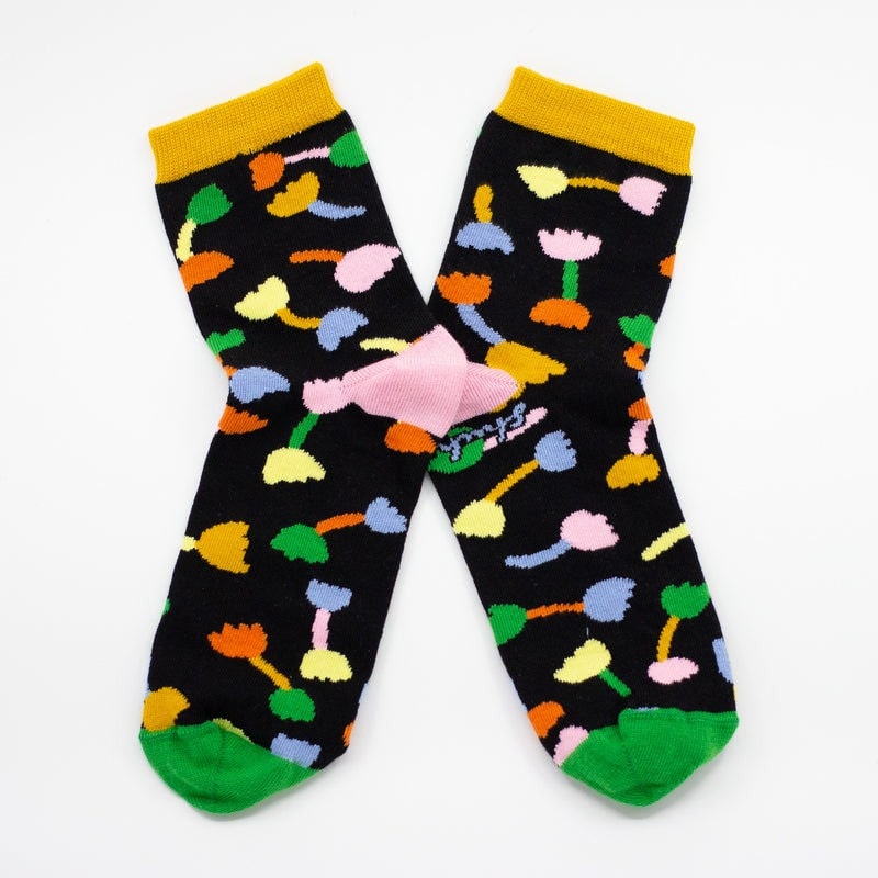 Shuh Lee Tulip Socks: A super cute design with a black backdrop and multicoloured tulips scattered across with green, pink and yellow splashes of colour at the top, heel and toe. 