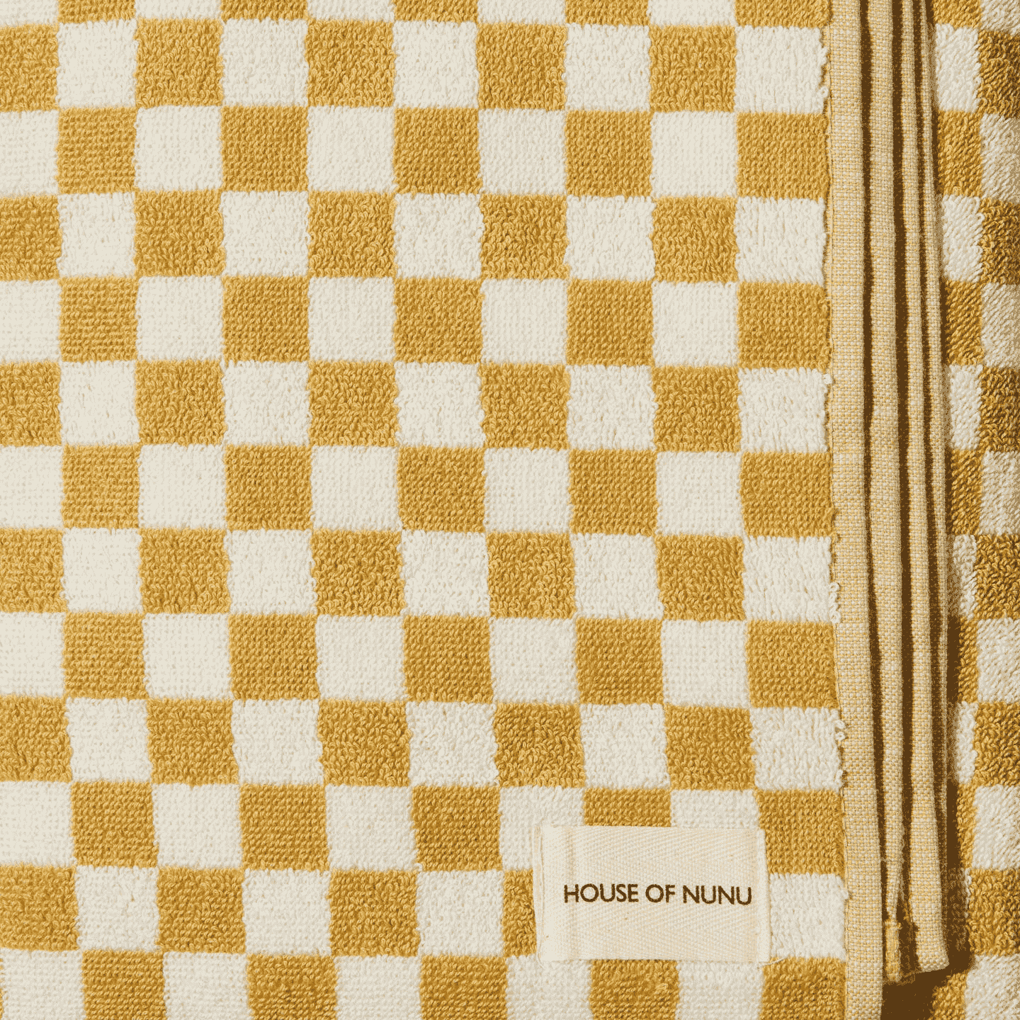 A close up of a white and yellow check hand towel. 